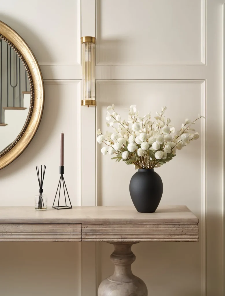 Faux flower entry arrangement with warm light and mirror