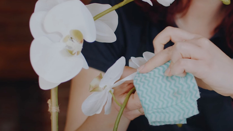 staff learning how to dust artificial flowers in place in hotel lobby