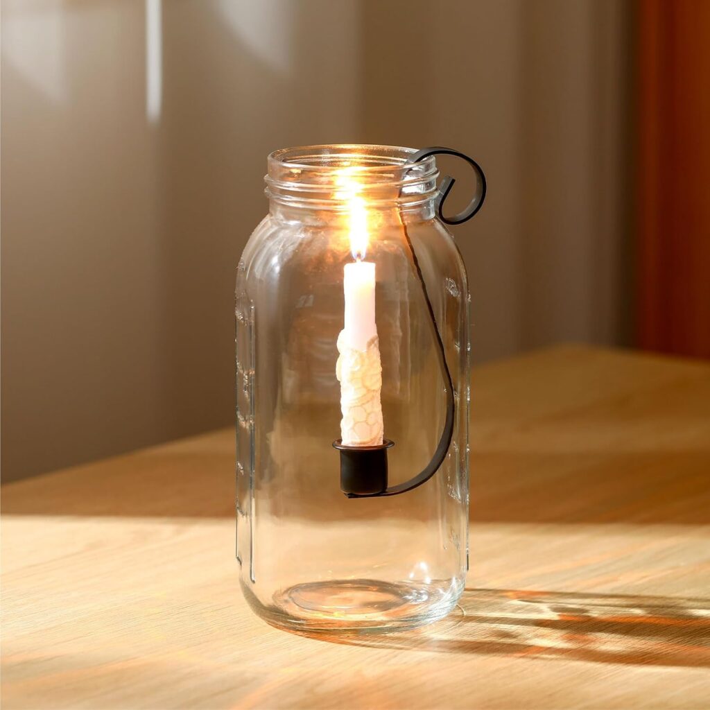 single mason jar candle holder insert with lit taper candle on wooden side table in warm farmhouse room