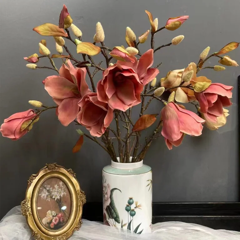 Pink artificial magnolia flower stems in a decorative ceramic vase