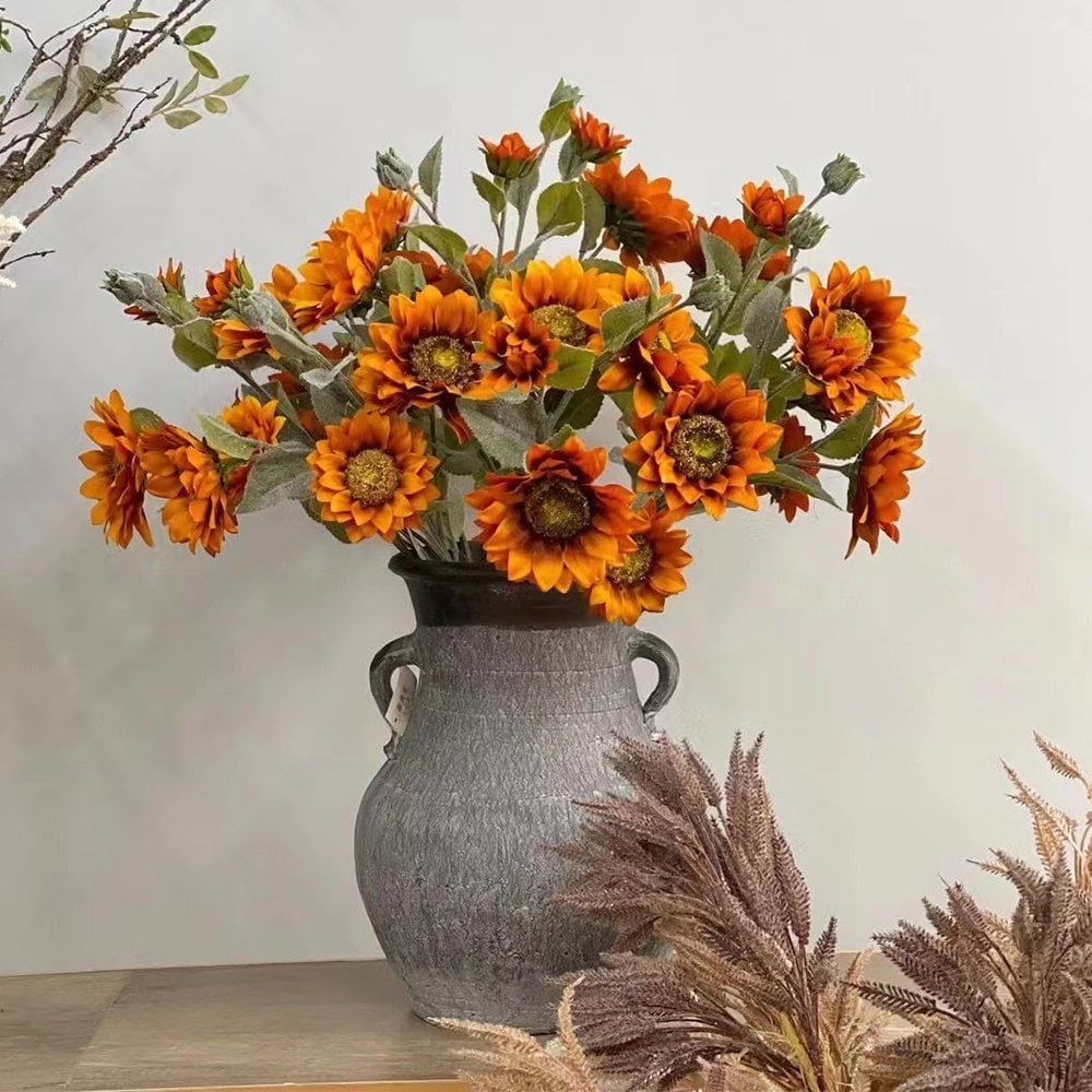 Orange artificial sunflower bouquet in a textured grey vase