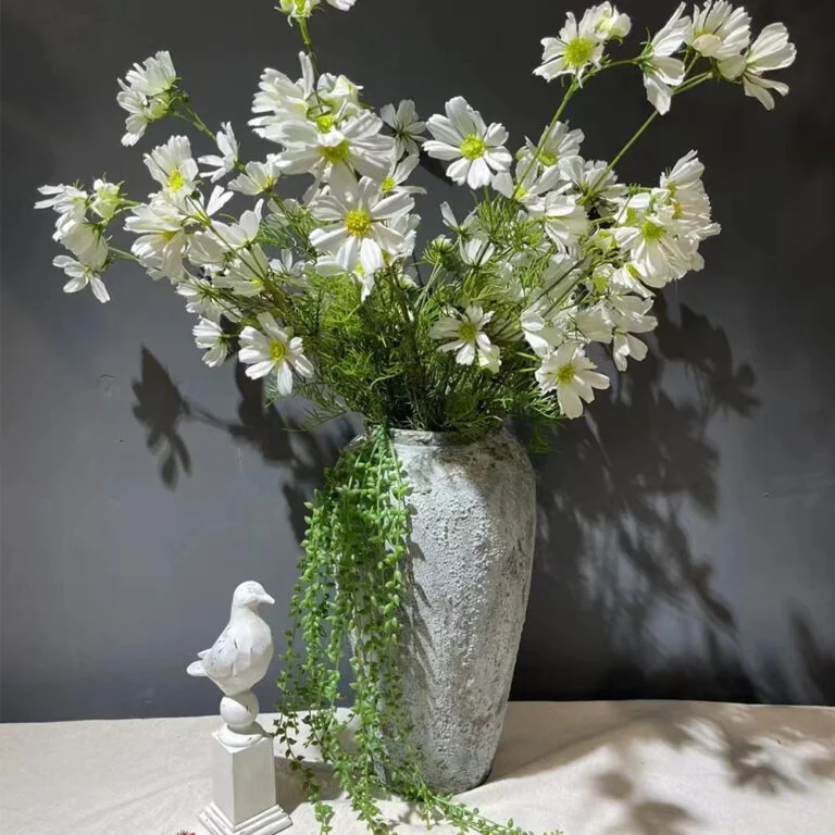 White artificial cosmos flower arrangement in a tall grey vase