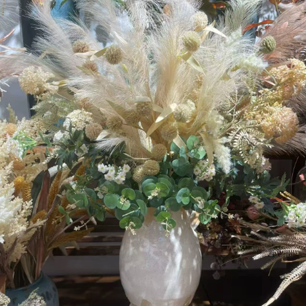 Neutral artificial pampas grass and eucalyptus arrangement in a white ceramic vase