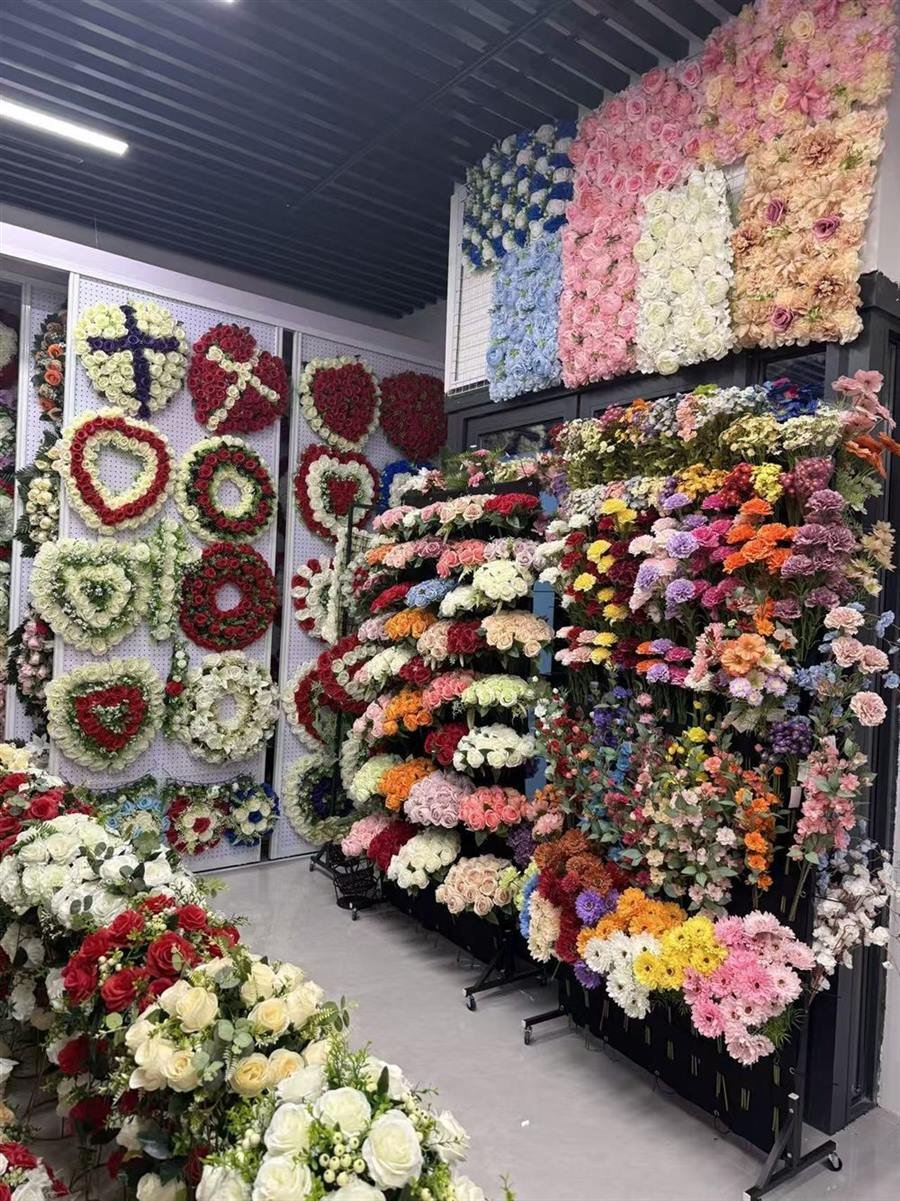 Artificial flower bouquets on racks and heart and cross wreaths on a showroom wall