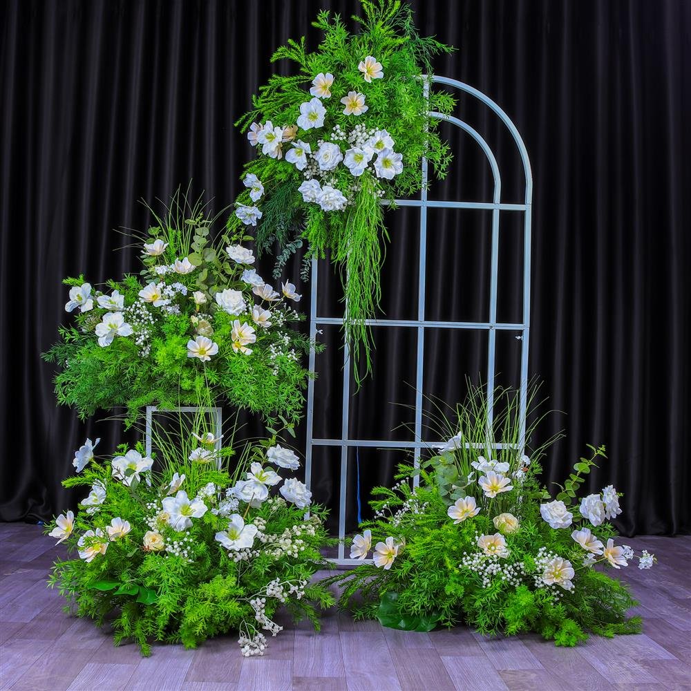 Green and white hanging artificial flowers on a round-top wedding arch with floor arrangements