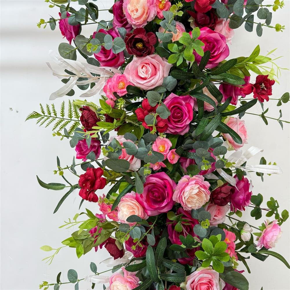 Close-up of burgundy and pink roses with eucalyptus in an artificial arch garland
