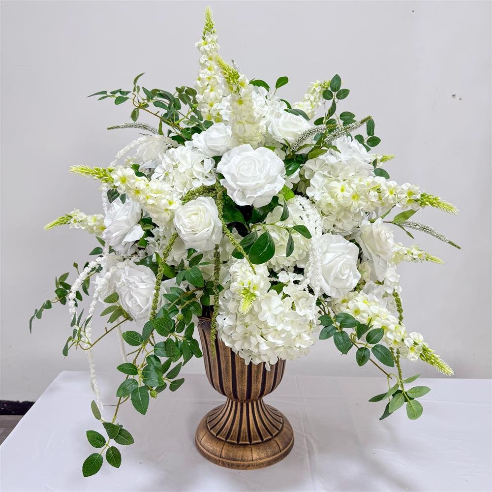 White rose and hydrangea artificial flower arrangement with trailing greenery in a bronze urn